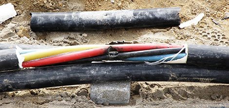 An underground electrical cable opened up in a trench showing the individual coloured cores